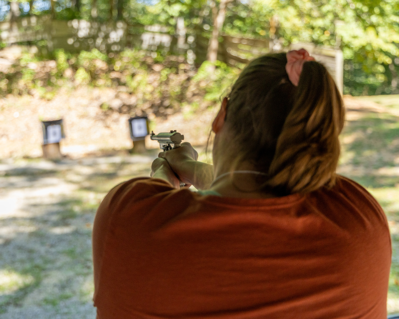 A woman firing down a handgun down an archery range