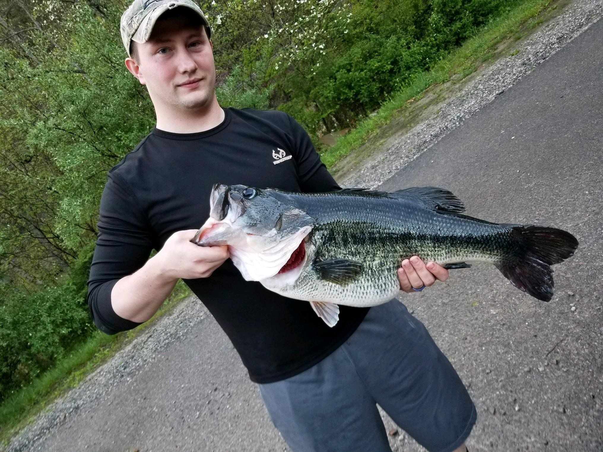 A young man is holding up a largemouth bass